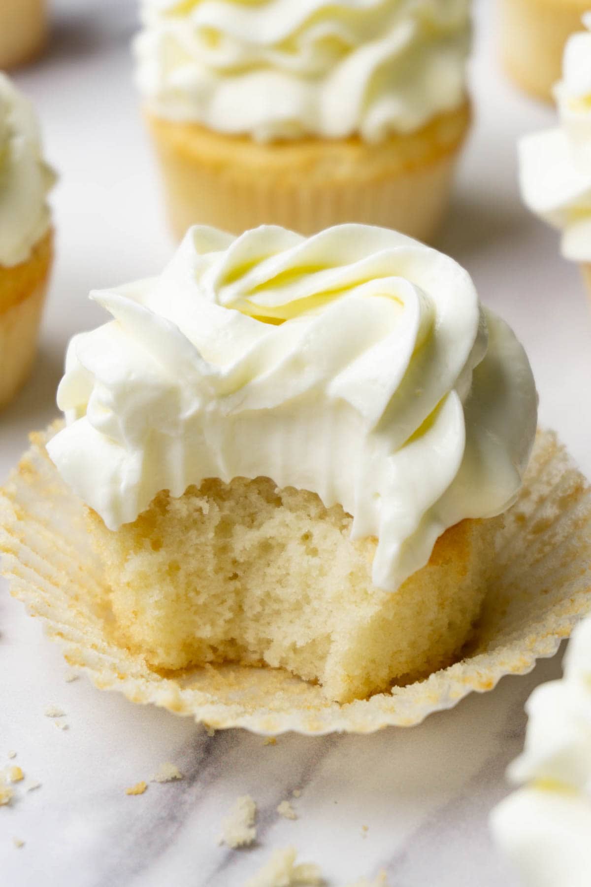 Vanilla cupcake with cream cheese frosting, one bite taken.