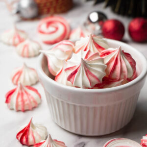Close up shot of a bowl filled with red and white meringue cookies.