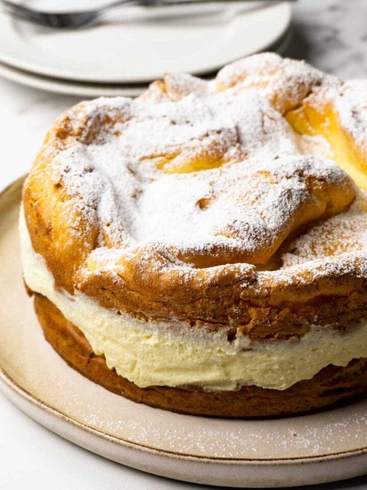 Polish cream cake dusted with powdered sugar on a large round plate.
