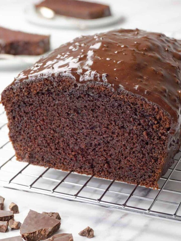 Sliced chocolate pound cake with dark chocolate glaze on a cooling rack.