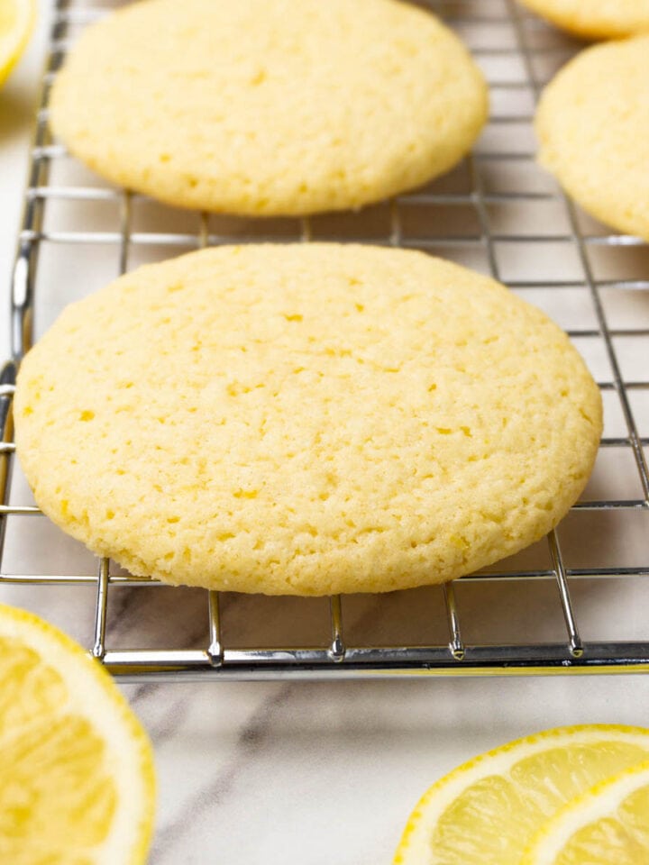 Lemon cookies on a cooling rack, fresh lemons are lying around.