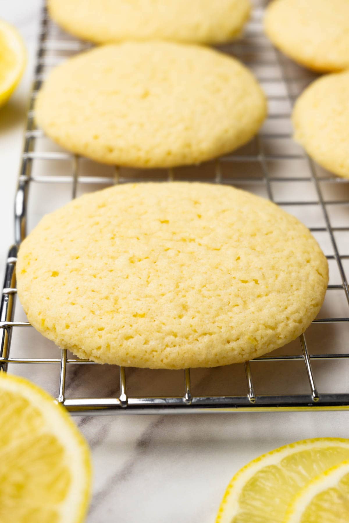 Lemon cookies on a cooling rack, fresh lemons are lying near.