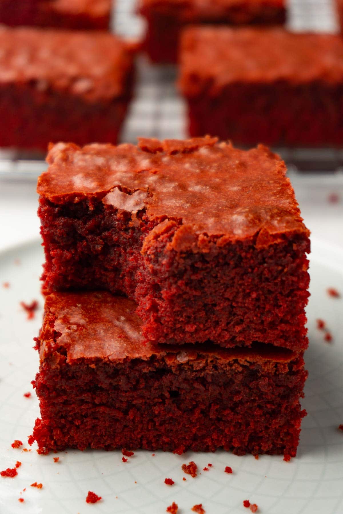 Two pieces of red velvet brownies stacked on top of each other, one bite taken from the top piece.