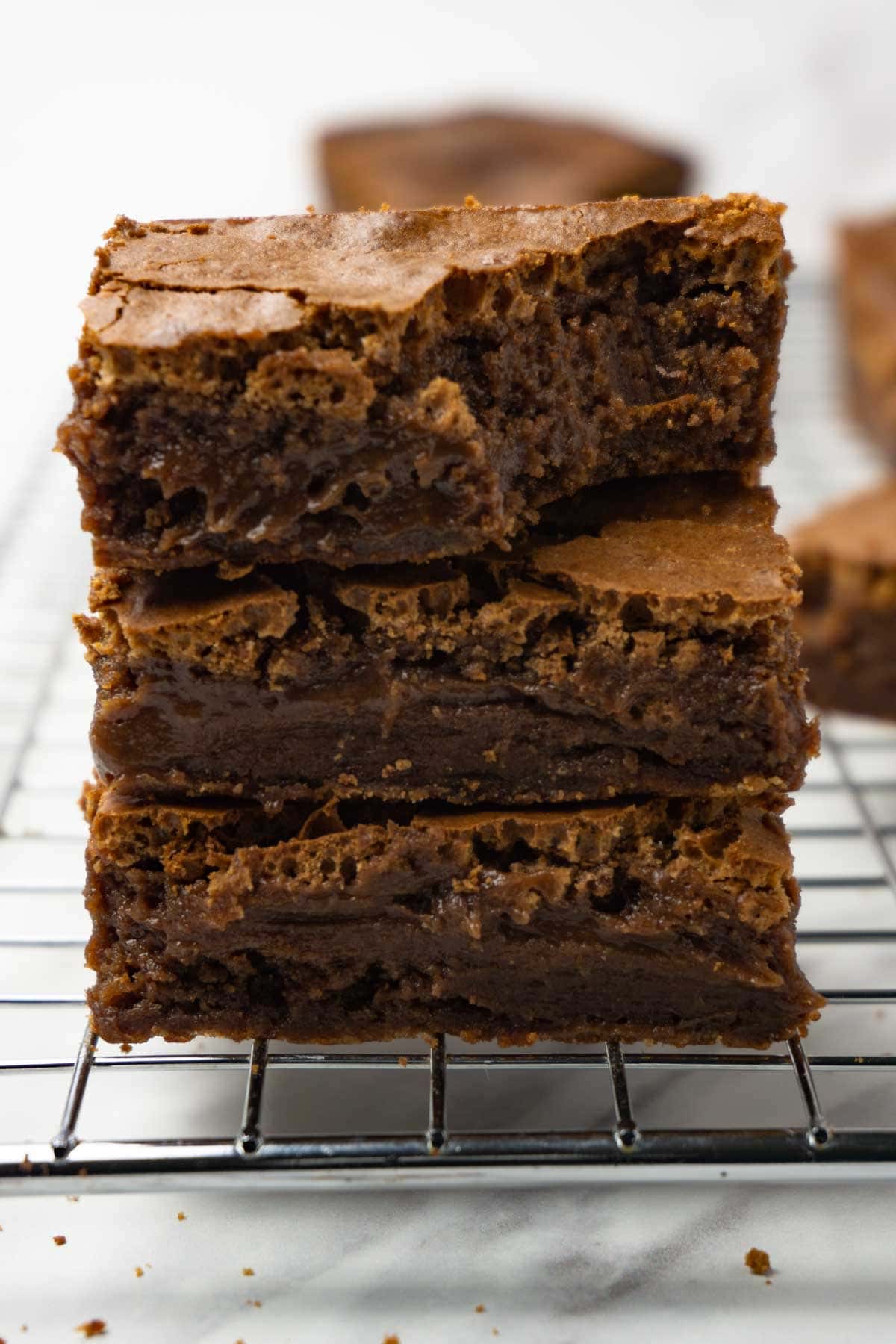 Three brownies stacked on top of each other, one bite taken from the top one.