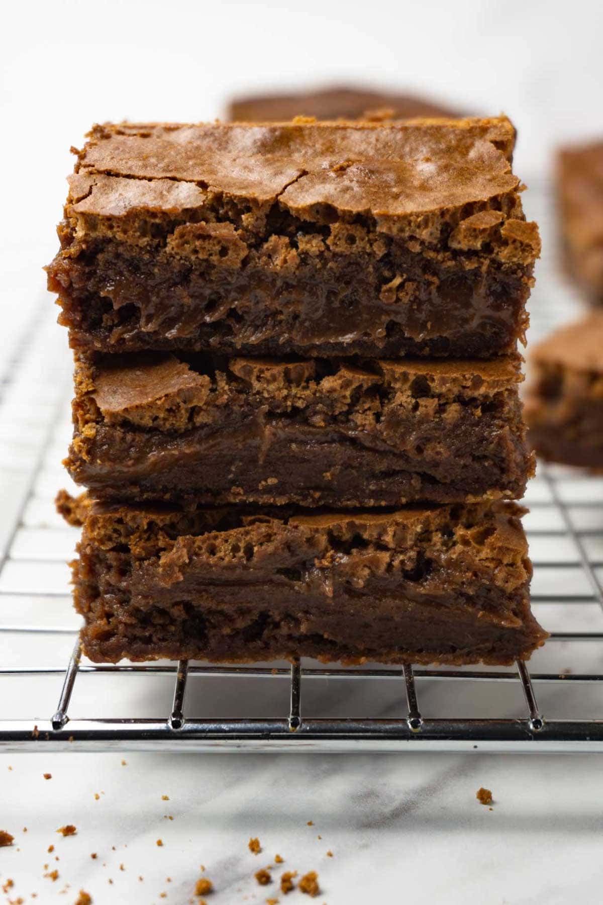 Three brownies are stacked on top of each other on a metal cooling rack.