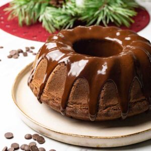 Chocolate Bundt cake with dark chocolate ganache glaze on a round serving plate.