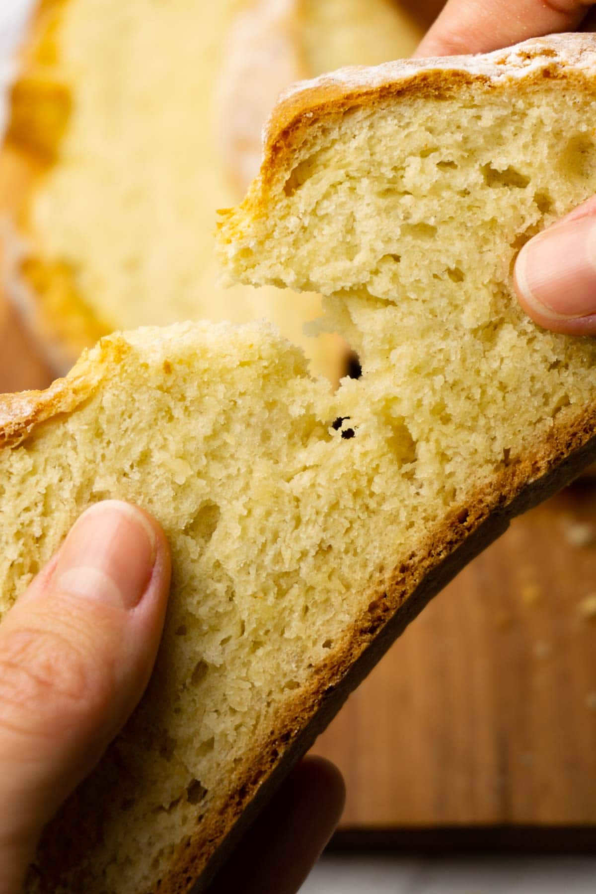 Hands ripping apart a slice of soda bread.