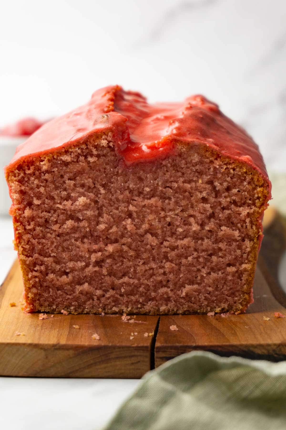 Strawberry pound cake with a strawberry sugar glaze on a wooden serving board, few slices are taken.