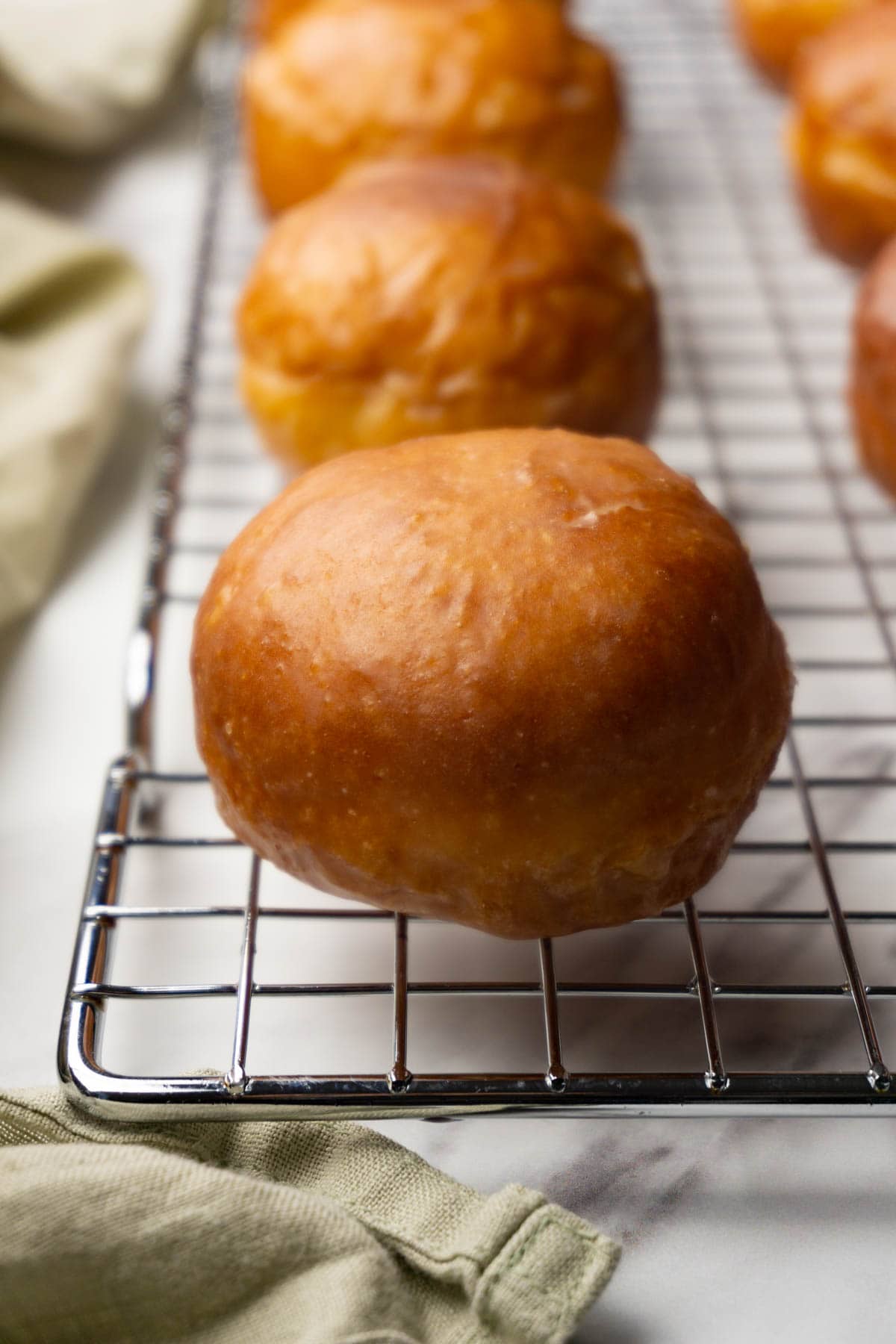Donut holes covered in sugar glaze are on a metal cooling rack.