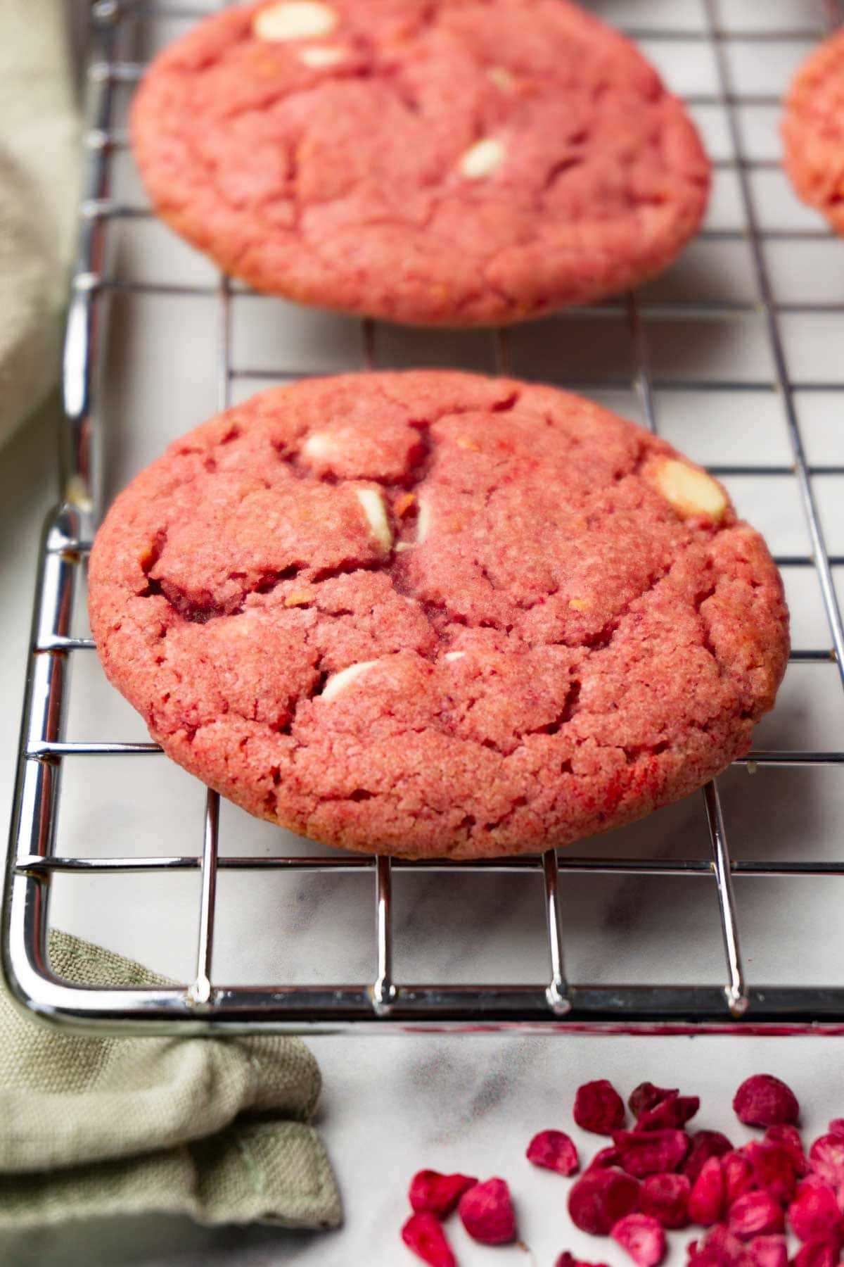 Raspberry cookies with white chocolate chips are lying on a wire rack.