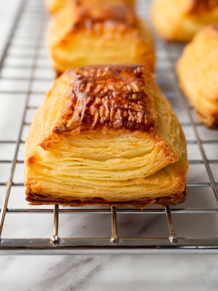 Extremely flaky rectangular pieces of baked Danish pastry on a cooling rack.