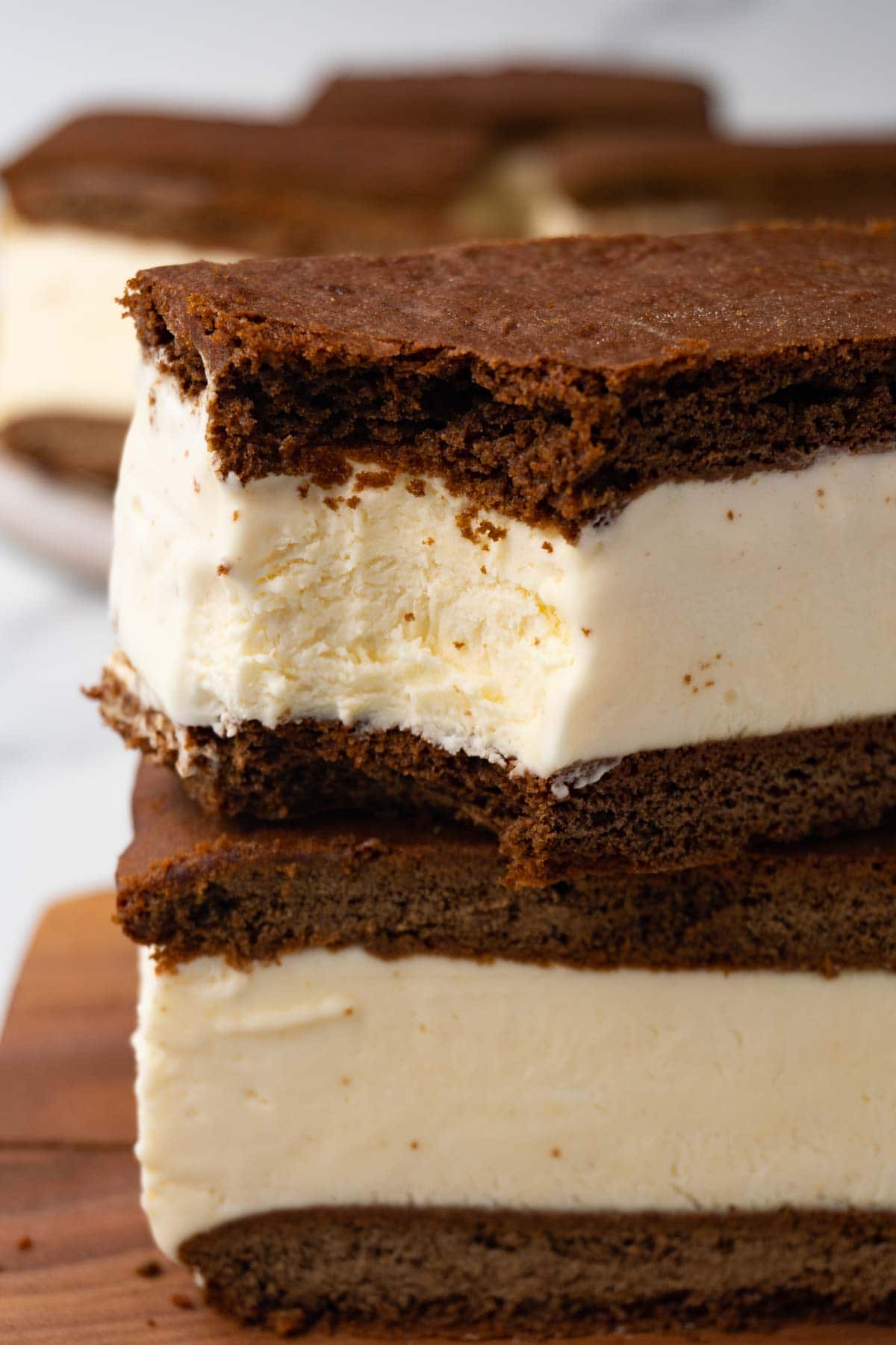 Vanilla ice cream sandwiches with chocolate cookies stacked on top of each other; one bite was taken.
