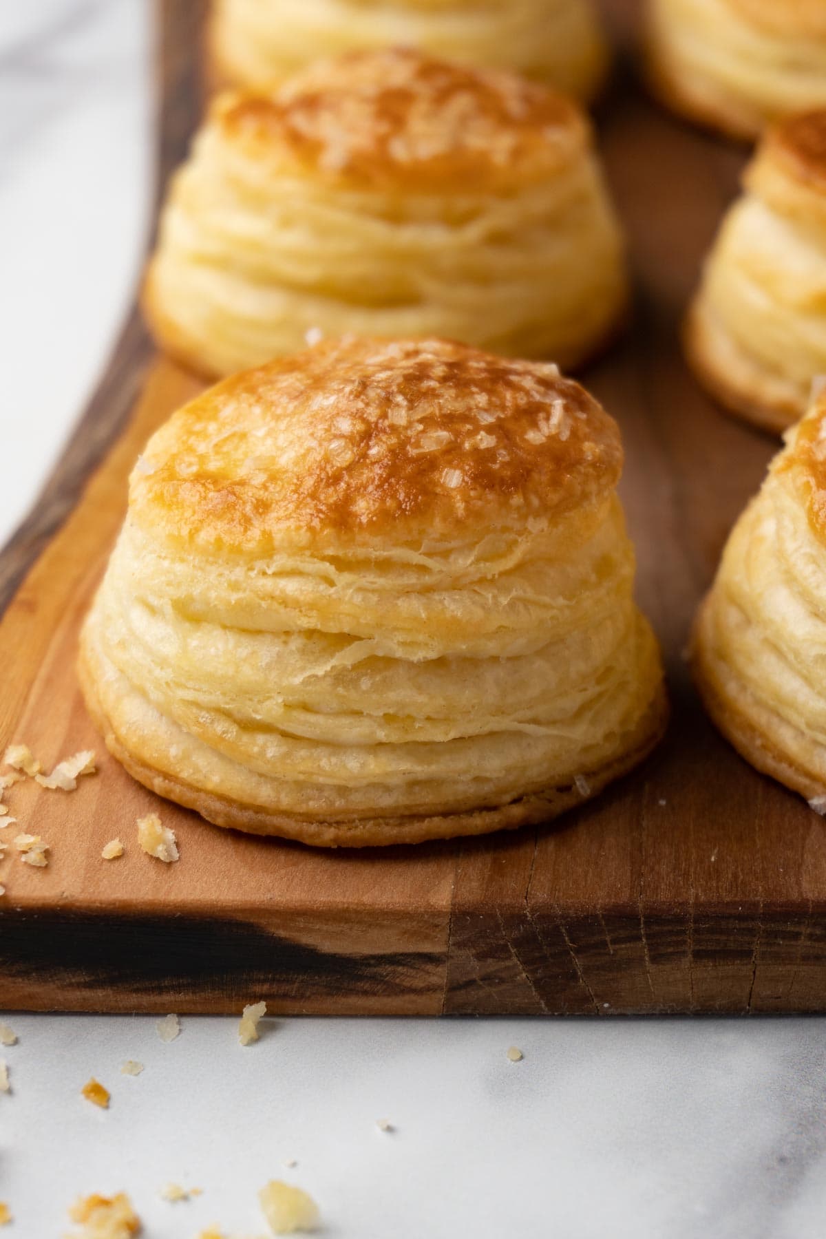 A freshly baked pieces of homemade puff pastry topped with sea salt flakes served on a wooden board.