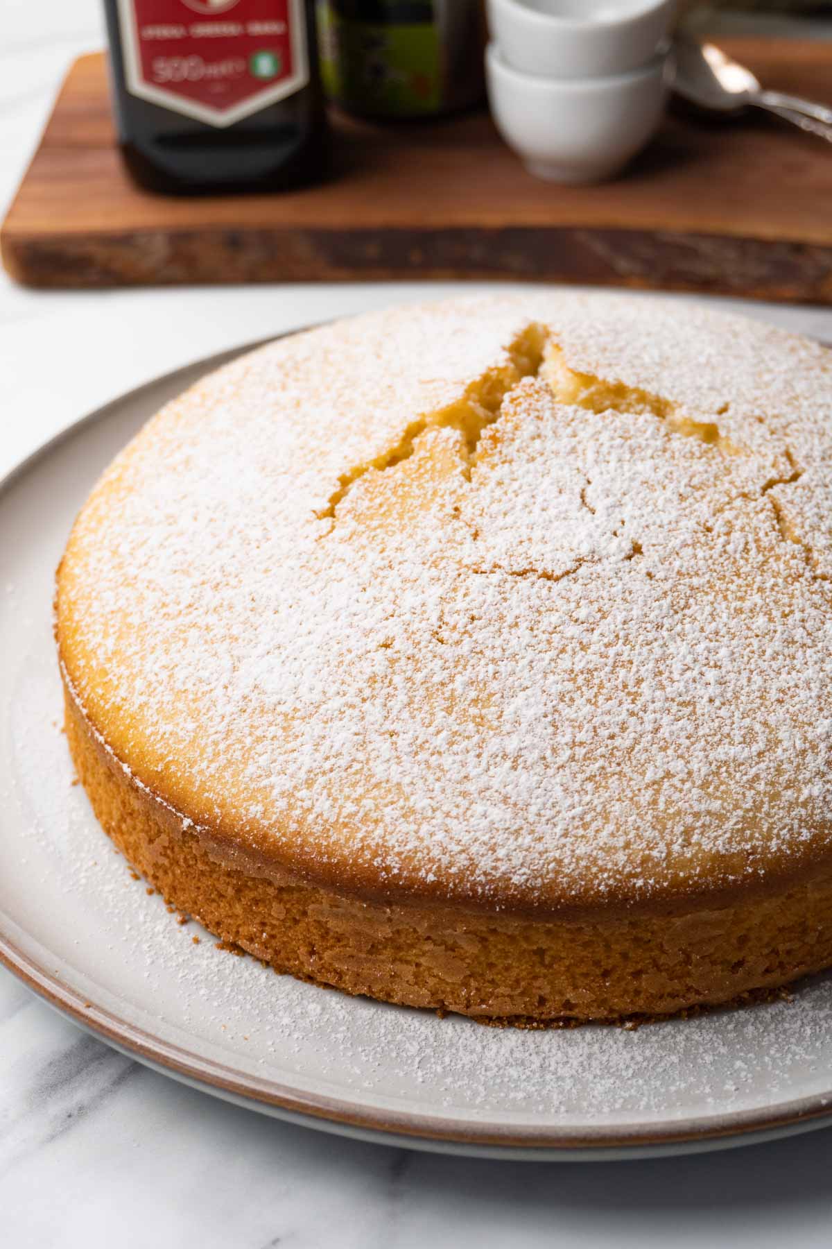 A round cake dusted with powdered sugar on a large round plate.