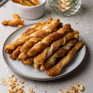 Puff pastry twists with cinnamon sugar topping on a round plate.