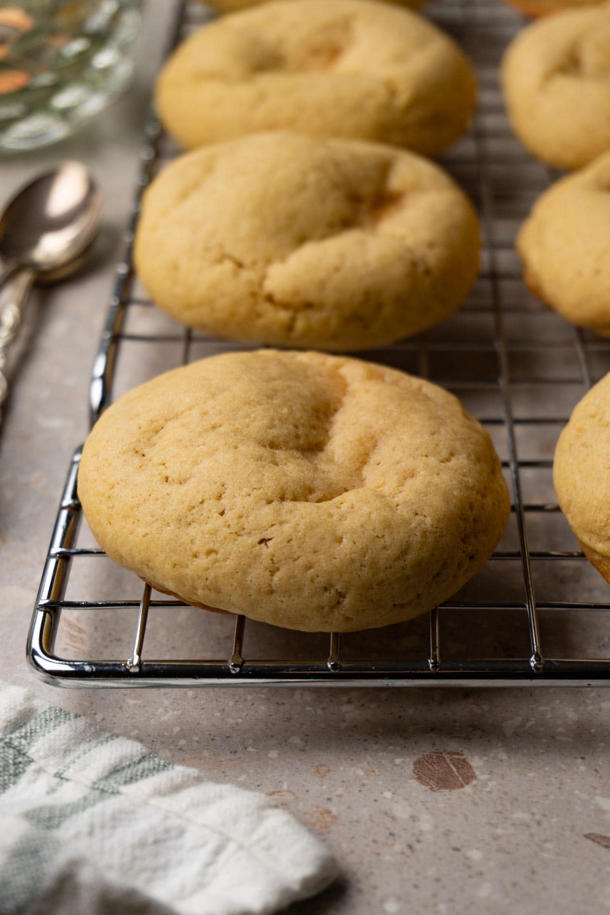 Vanilla cheesecake cookies on a metal cooling rack.