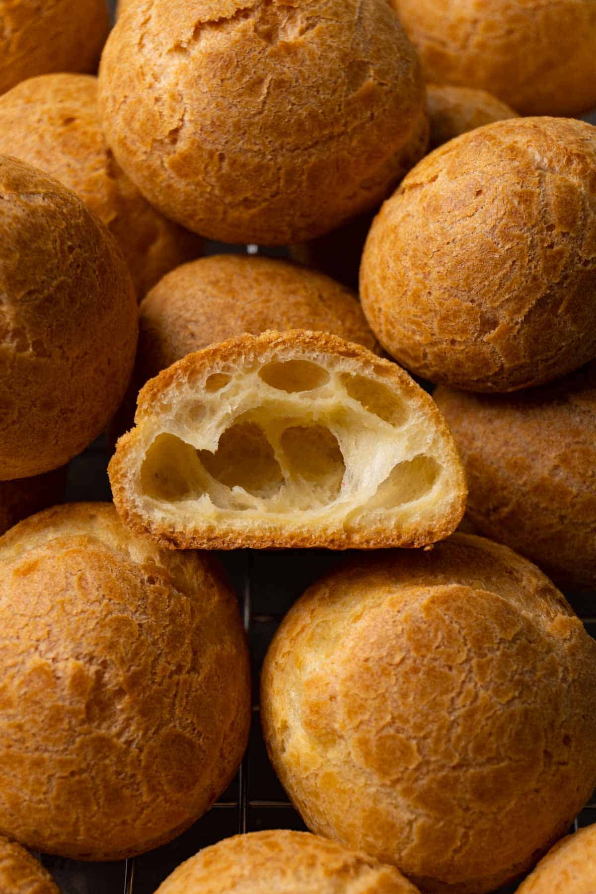 Cream puff shells on a cooling rack. One shell was cut in half.