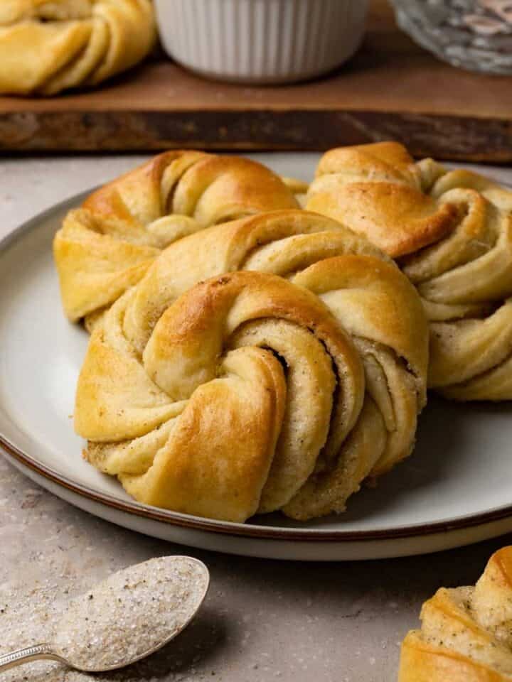 Three cardamom buns are served on a small round plate.