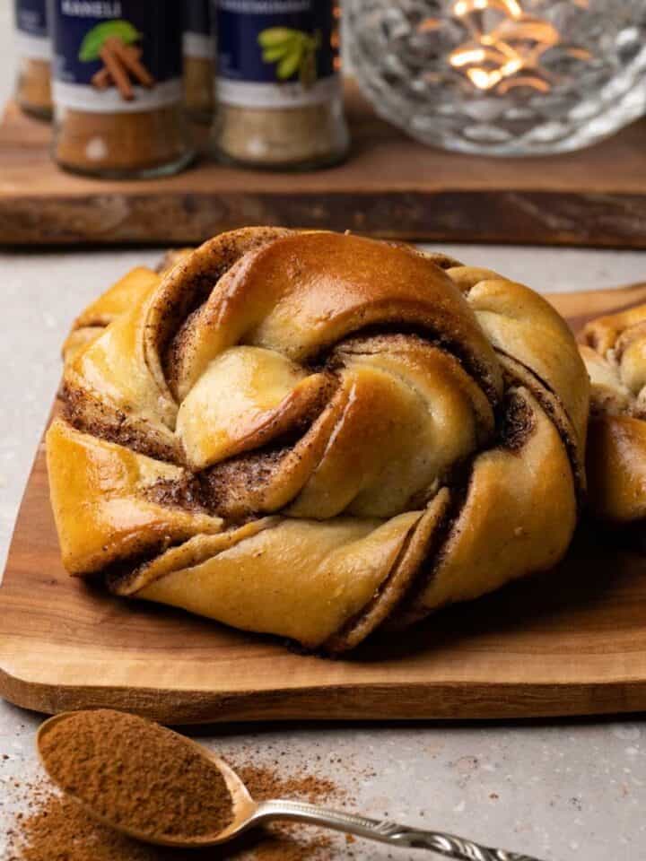 Cinnamon buns are served on a small wooden board.