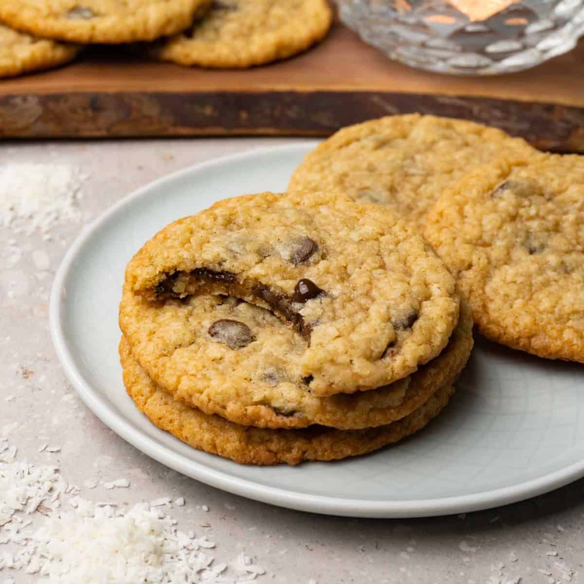 Cookies with chocolate chips are served on a plate. One bite was taken from one of the cookies.