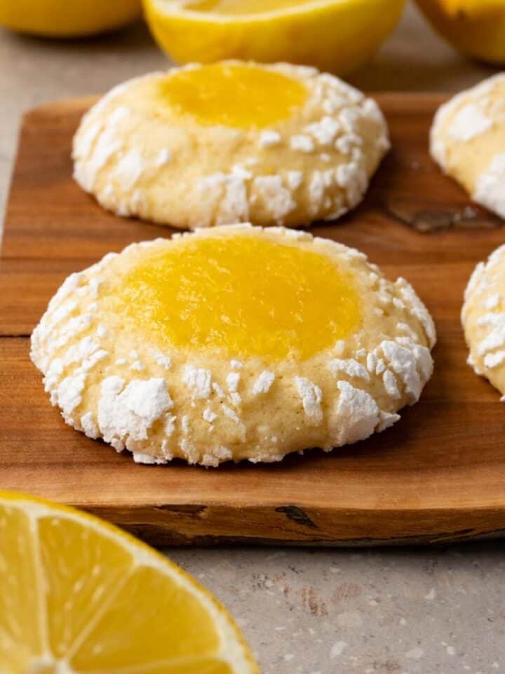 Crinkle cookies filled with lemon curd are served on a wooden board.