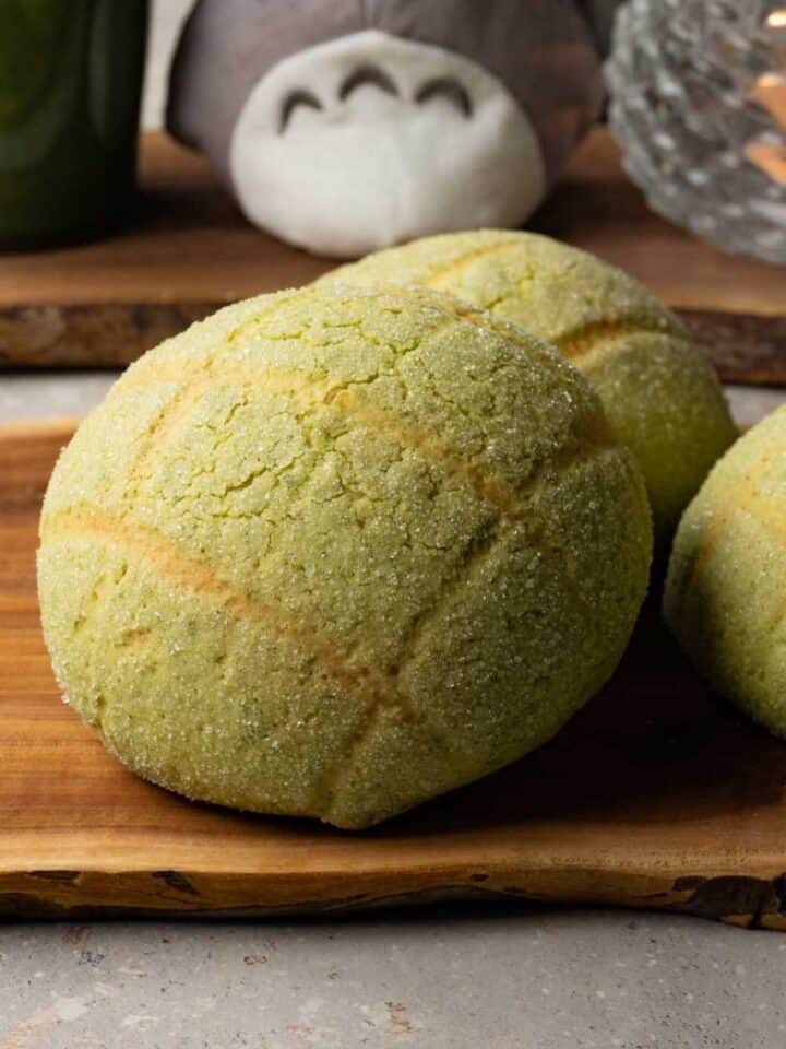 Three green buns on a wooden board.