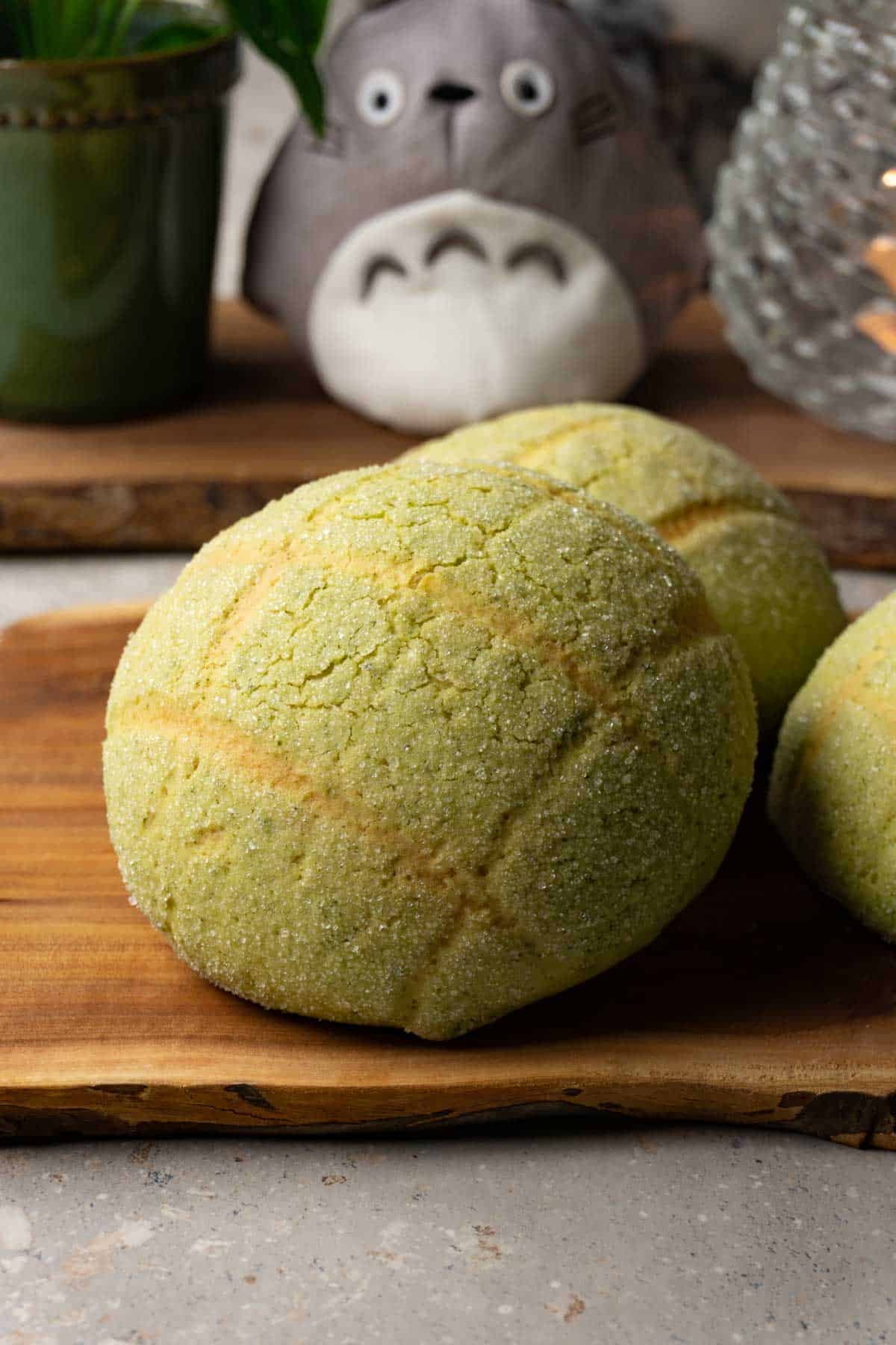 Three green buns on a wooden board.