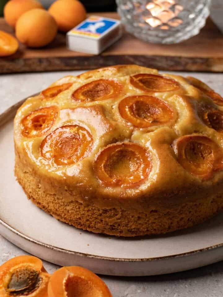 Cake with caramelised peaches topping on a large round plate.