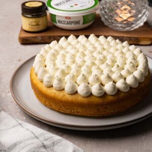 A single-layer cake with frosting piped on top, served on a large round plate.
