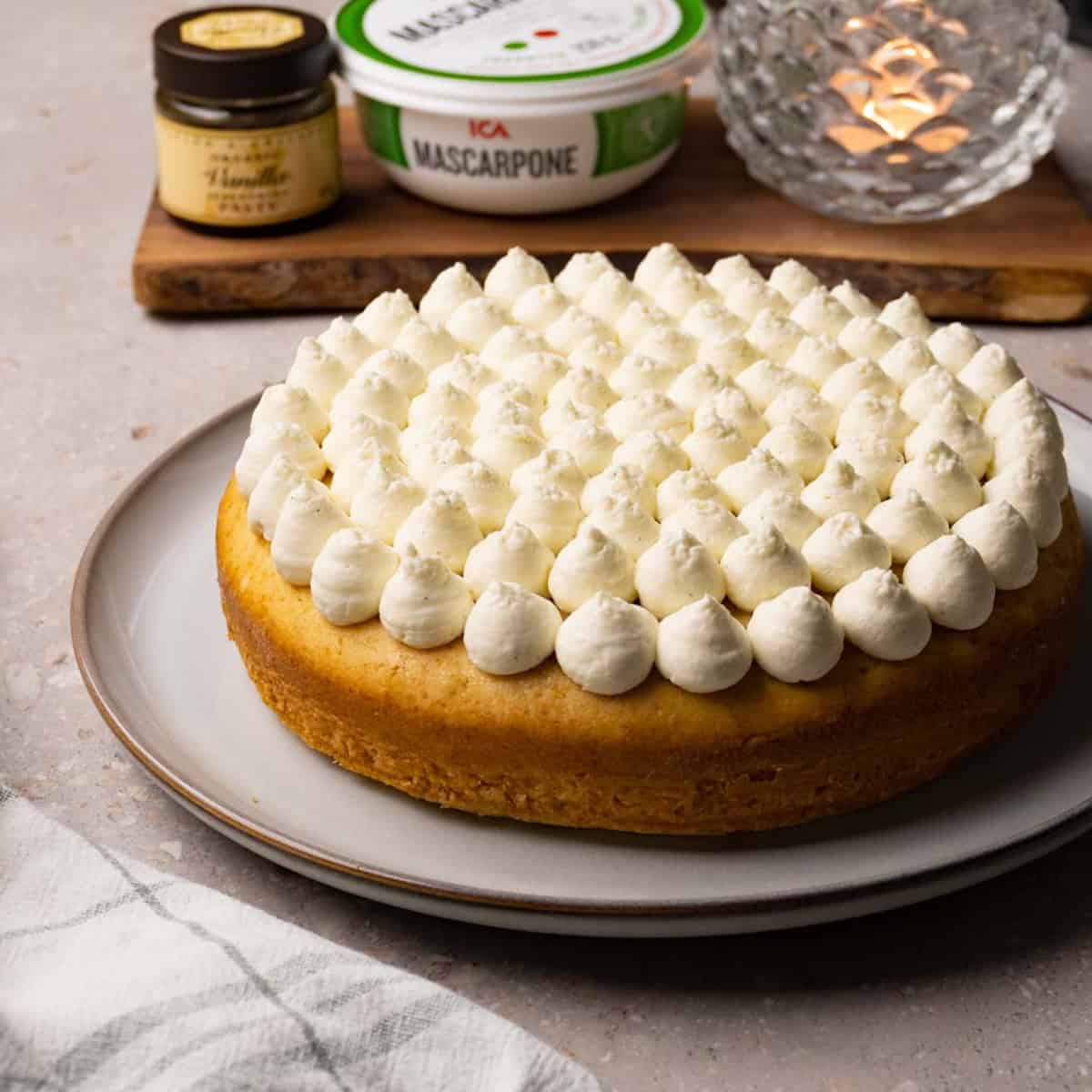 One layer cake with mascarpone cream topping on a large round plate.