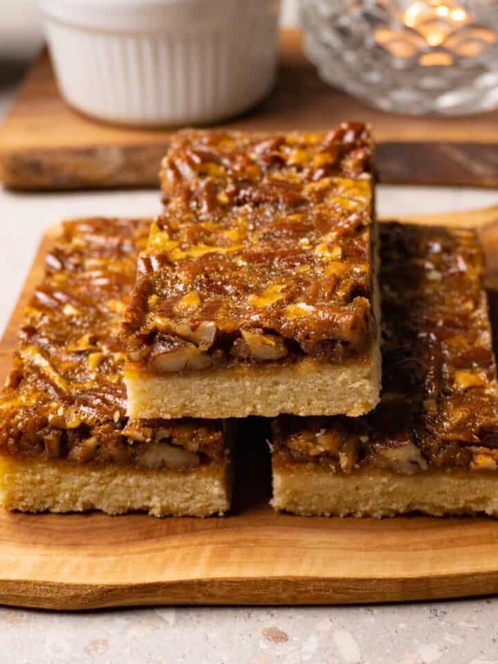 Three pecan bars on a wooden board.