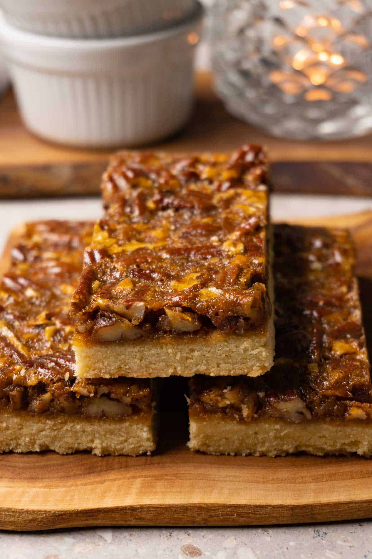 Three pecan bars on a wooden board.
