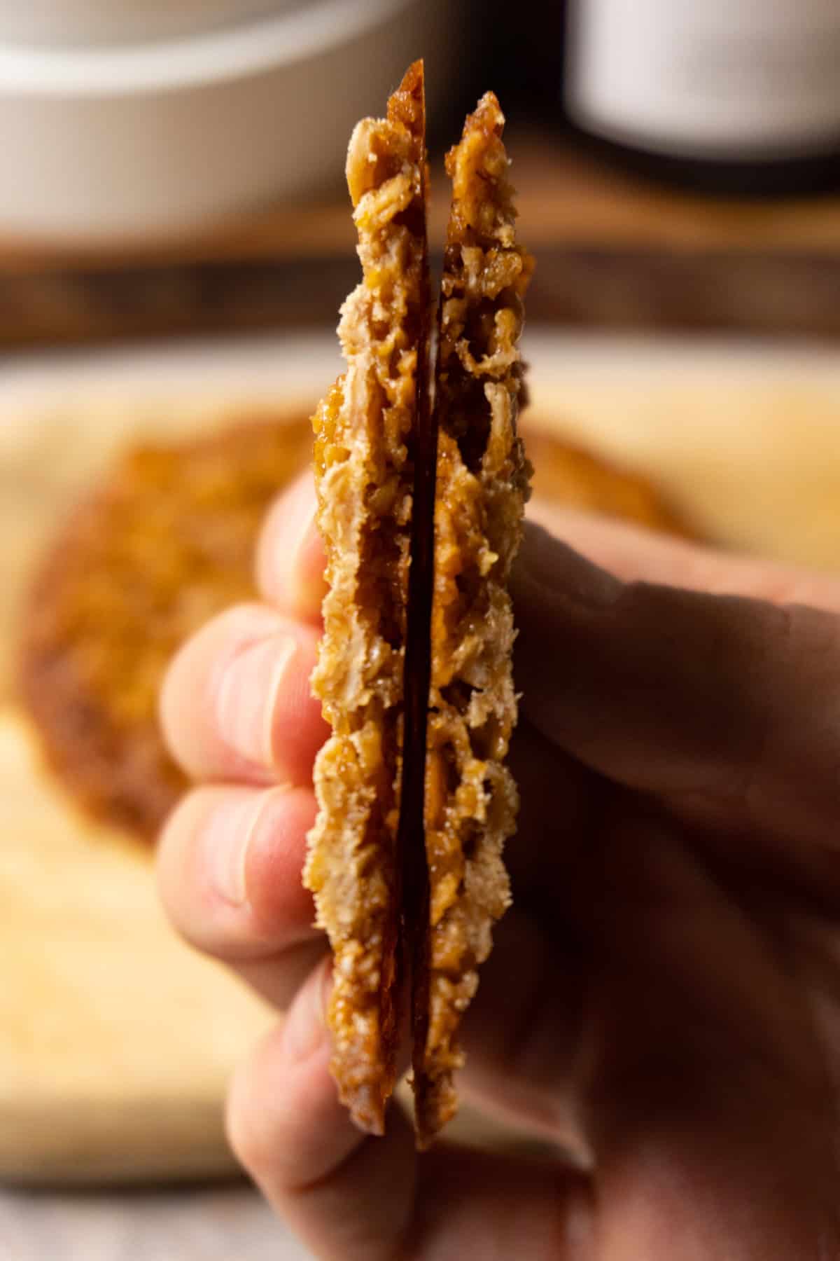 A hand is holding a lace cookie cut in half.