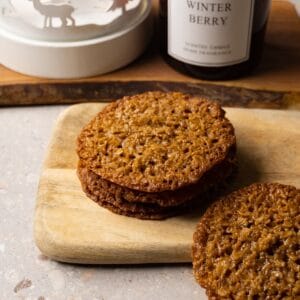 Lace cookies stacked on a wooden board.