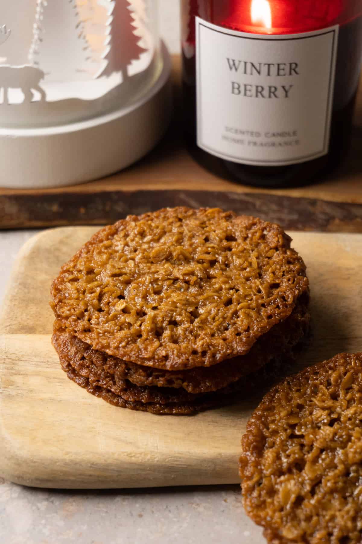 Lace cookies stacked on a wooden board.