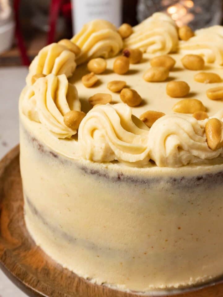 Chocolate peanut butter cake frosted with white chocolate ganache is served on a wooden cake stand.