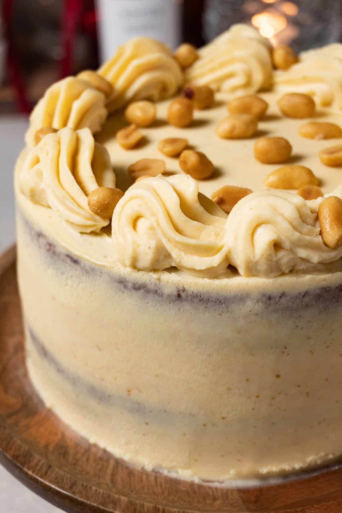 Chocolate peanut butter cake frosted with white chocolate ganache is served on a wooden cake stand.