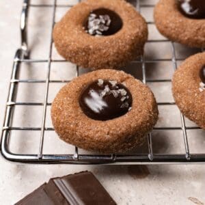 A chocolate cookie with a ganache-filled center on a metal rack.