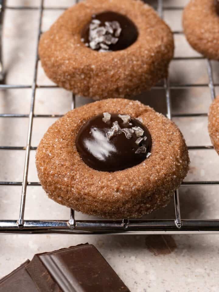 A chocolate cookie with a ganache-filled center on a metal rack.