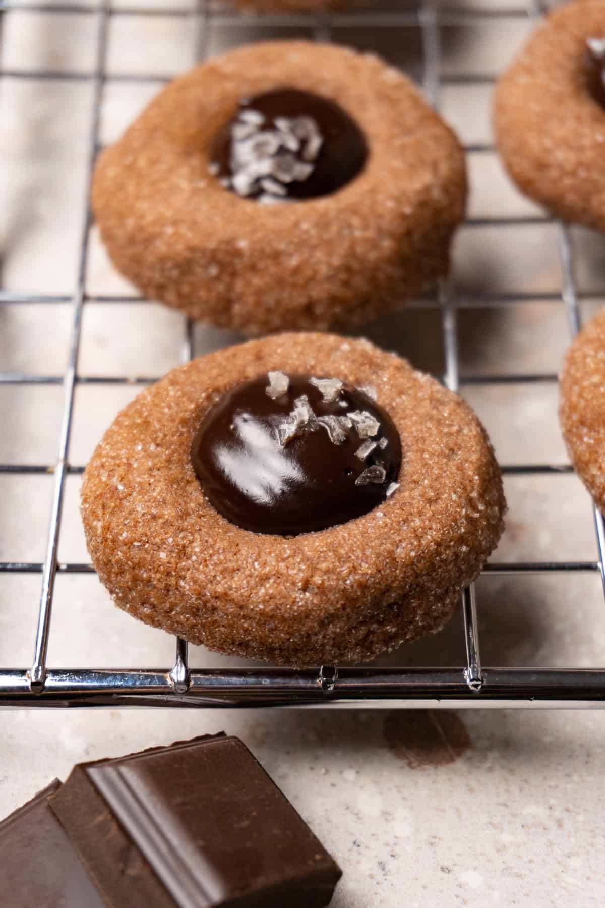 A chocolate cookie with a ganache-filled center on a metal rack.