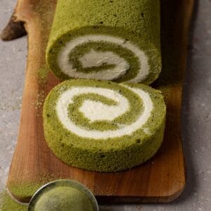 Matcha Swiss roll cake with cream cheese filling on a wooden board.