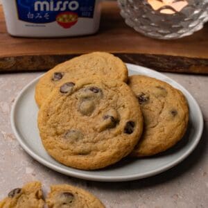 Chocolate chip cookies are served on a small round plate.