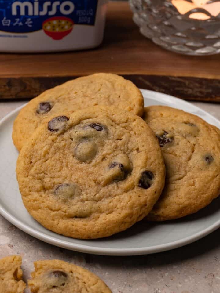 Chocolate chip cookies are served on a small round plate.