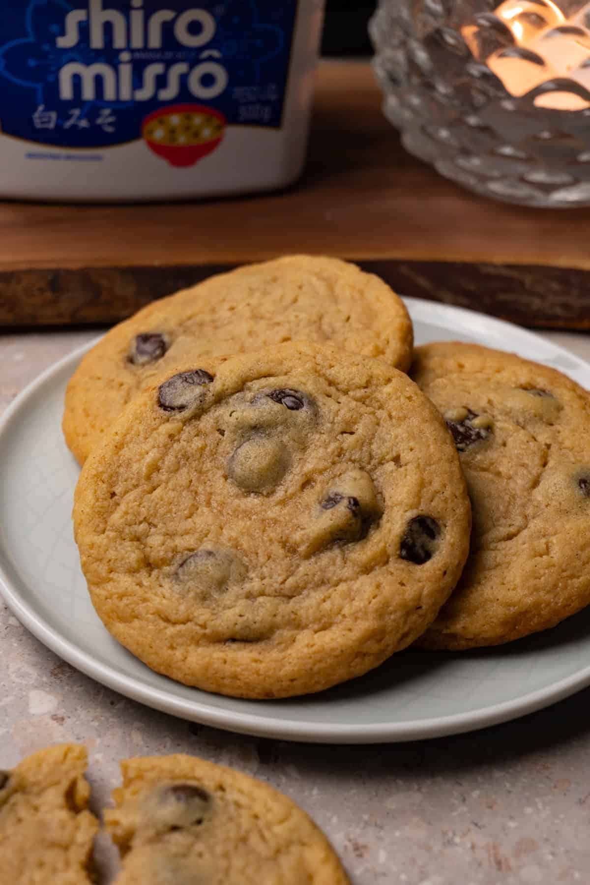 Chocolate chip cookies are served on a small round plate.