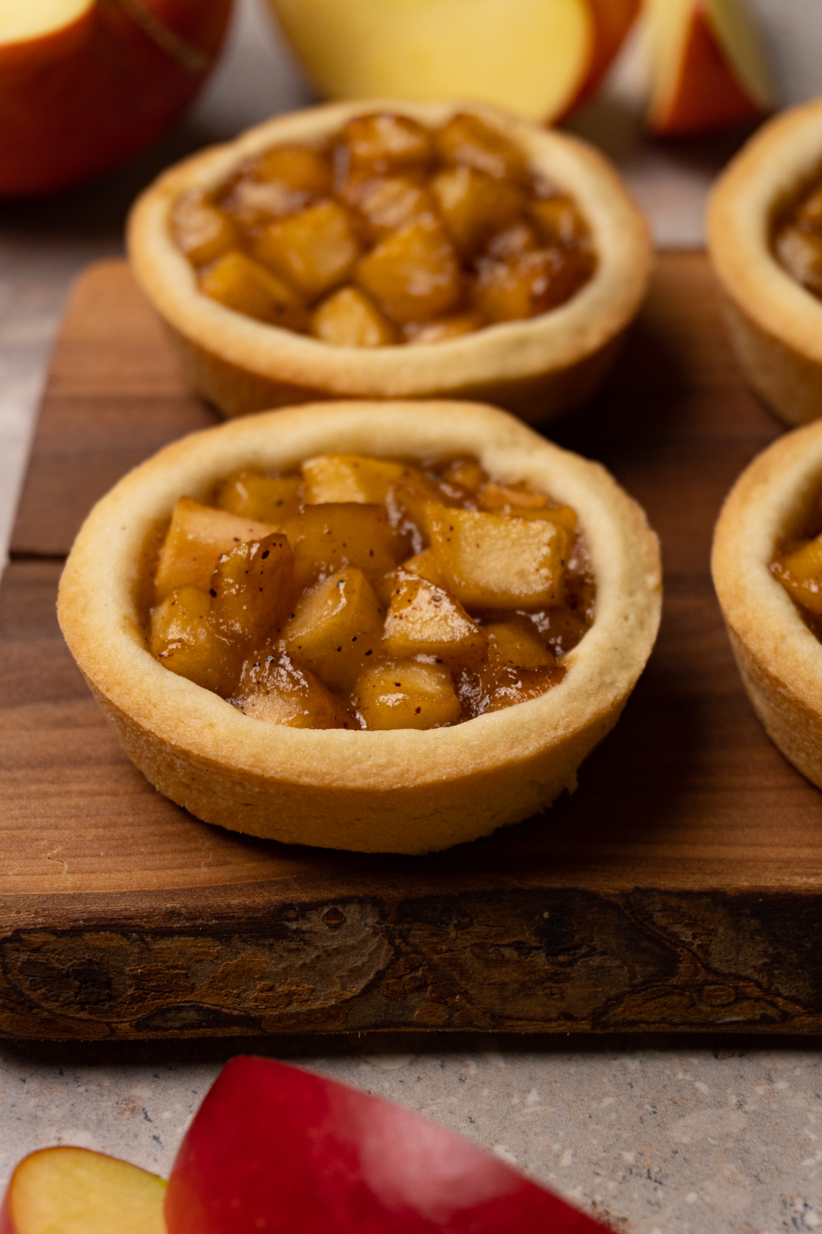 Cookies with an apple filling are served on a wooden board.